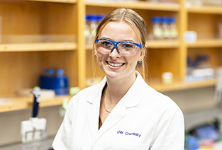 UW Chemistry student in lab coat smiling