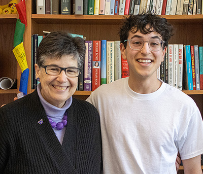 Tristan Jafari standing with UW President Ana Mari Cauce, with bookshelves in the background.