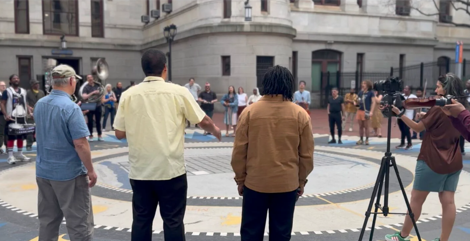 A circle of people playing and listening to music.