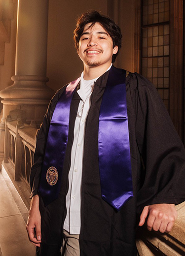 Devin Sampson-Craig posing in his graduation gown and sash.