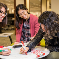 Three students working on a project together at a round table