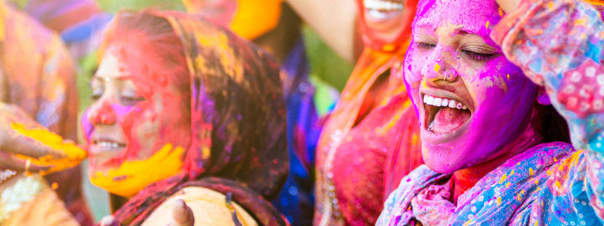 Two smiling students covered in colorful pigments during Holi