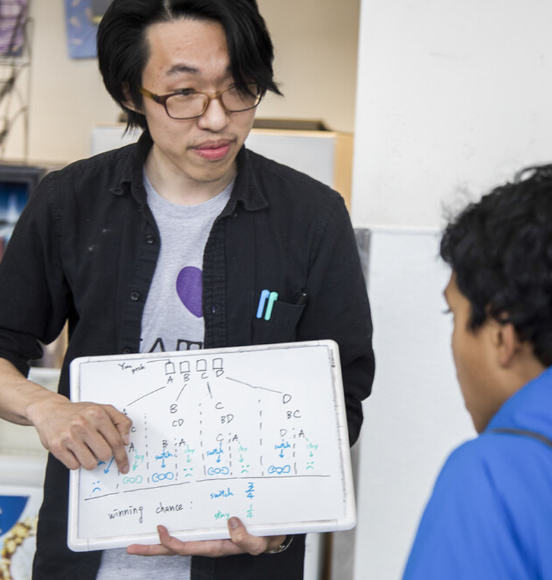 A student showing a probability problem to another student on a small dry erase board