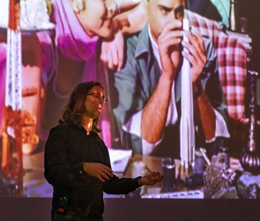 Person gives lecture in front of project screen showing classic TV shows.