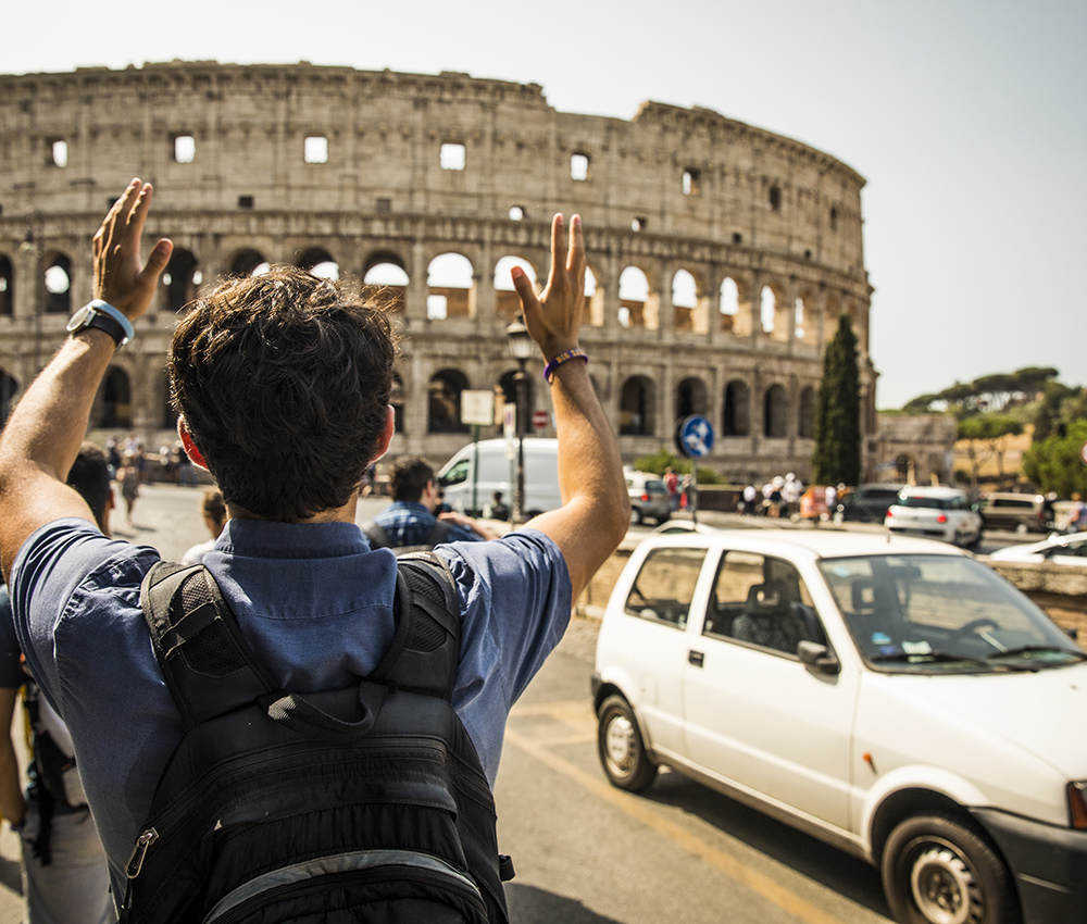 Student with outstretched arms near the Colosseum in Rome.