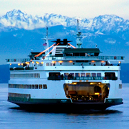 A Washington State Ferry travels in the Puget Sound with the Olympic Mountains in the background.