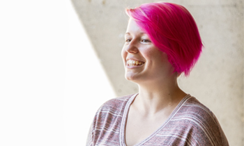 A student with pink hair smiling.