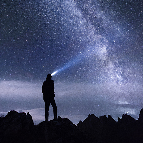 Person on mountain, looking at the night sky.