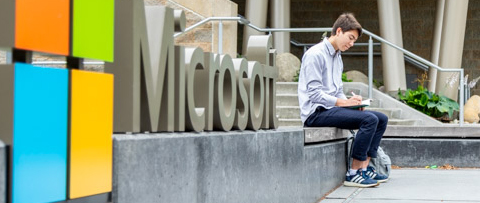 A student writes in his notebook as he sits outside the entrance of Microsoft.