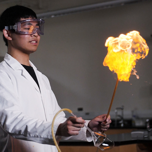 A student lights a methane bubble on fire in a lab experiment.