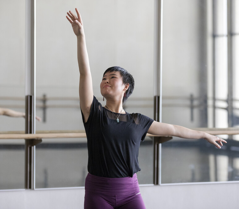 Dance student moving in front of ballet bar