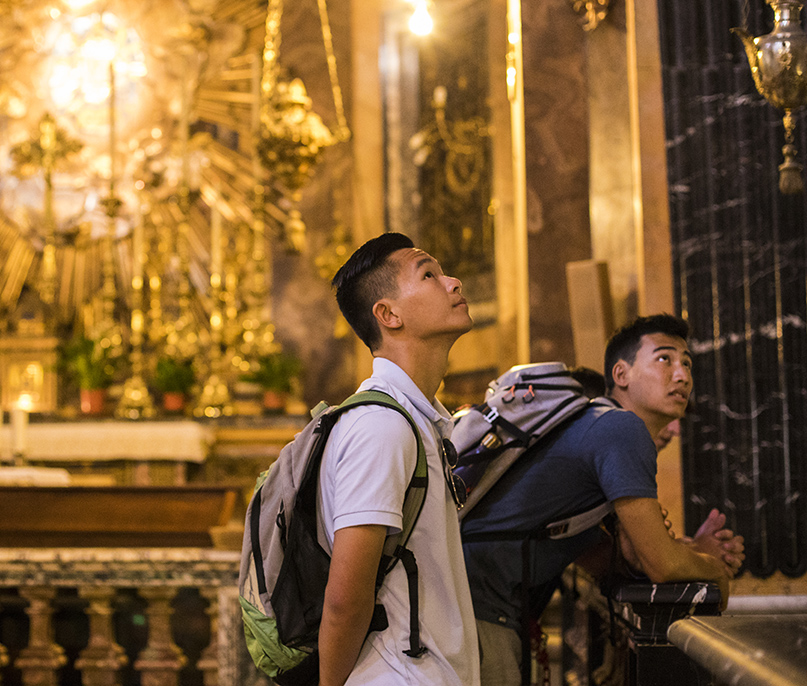 Students look up to view the ornate art in a cathedral in Rome, Italy.