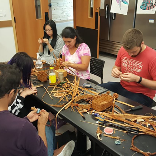 A group of students learning to weave baskets.