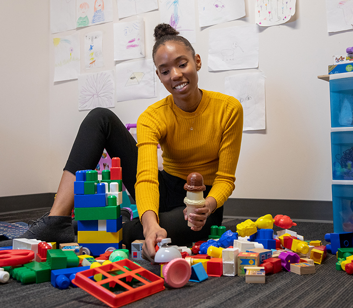 Deja Edwards surrounded by colorful toys in the Social Cognitive Development Lab.