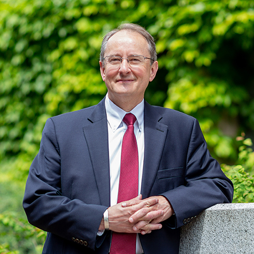 Dean Robert Stacey portrait on campus with greenery behind him.