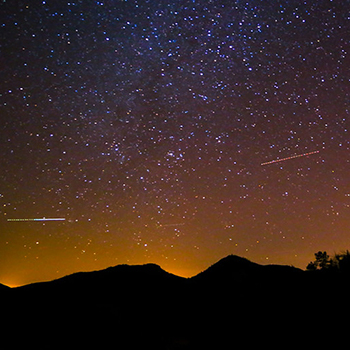 Starry sky with silhouetted mountains.