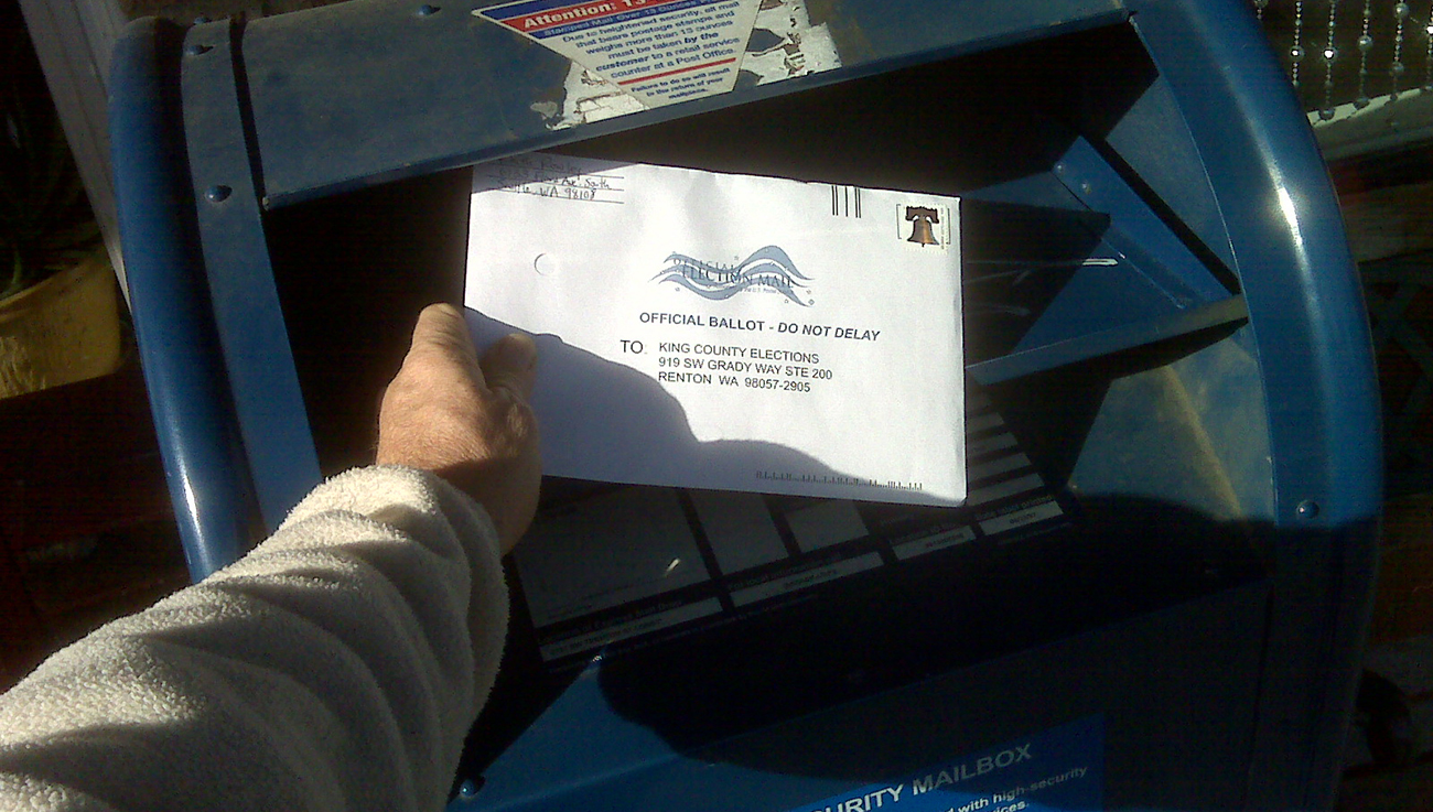 Person putting mail-in ballot into mailbox.