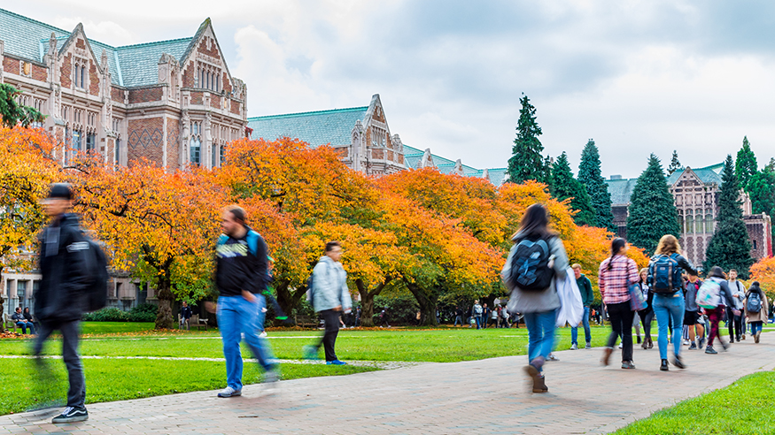 Students crossing the quad in fall, with golden leaves on the trees