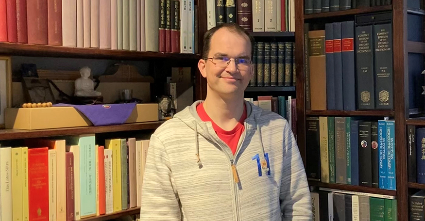 Andrew Glass in front of shelves of books.