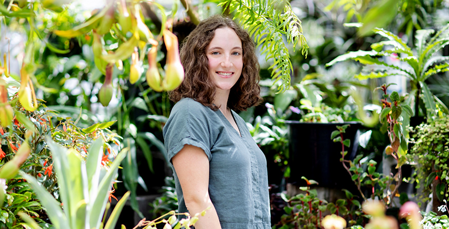 Ava Kloss-Schmidt surrounded by plants in the UW Biology Greenhouse