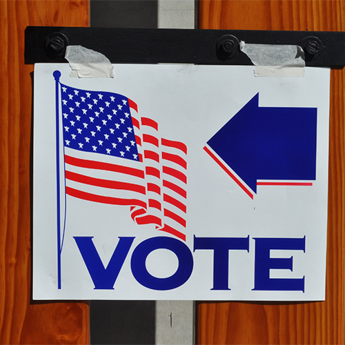 Sign with "Vote" and American flag on it, at a voting location.