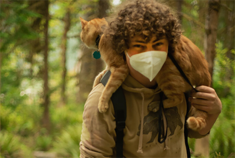 Arthur Obst on a walk in the woods with his cat draped over his shoulder. 