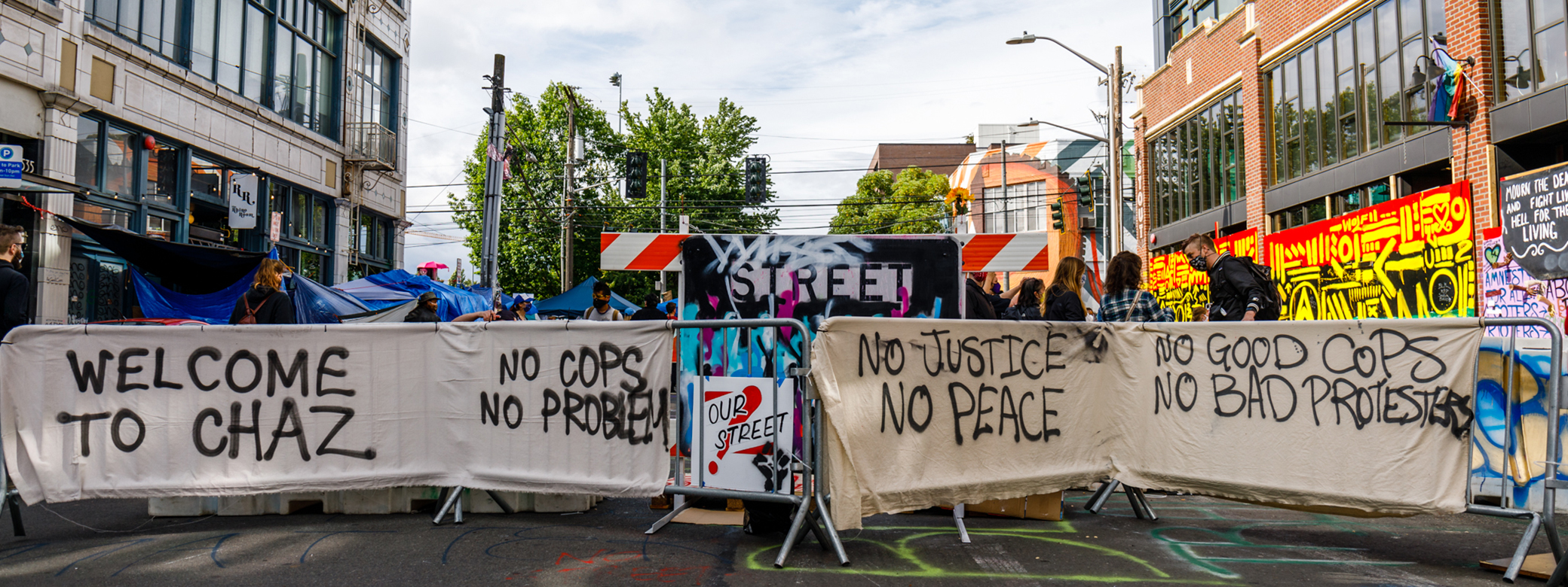 Scene from the CHOP, with protest signs attached to metal barriers. 