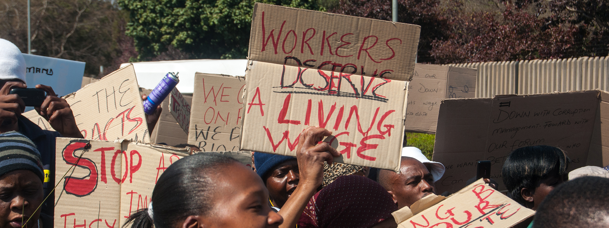 Protesters at a rally hold up signs about deserving a living wage. Photo credit: Meraj Chhaya/Flickr
