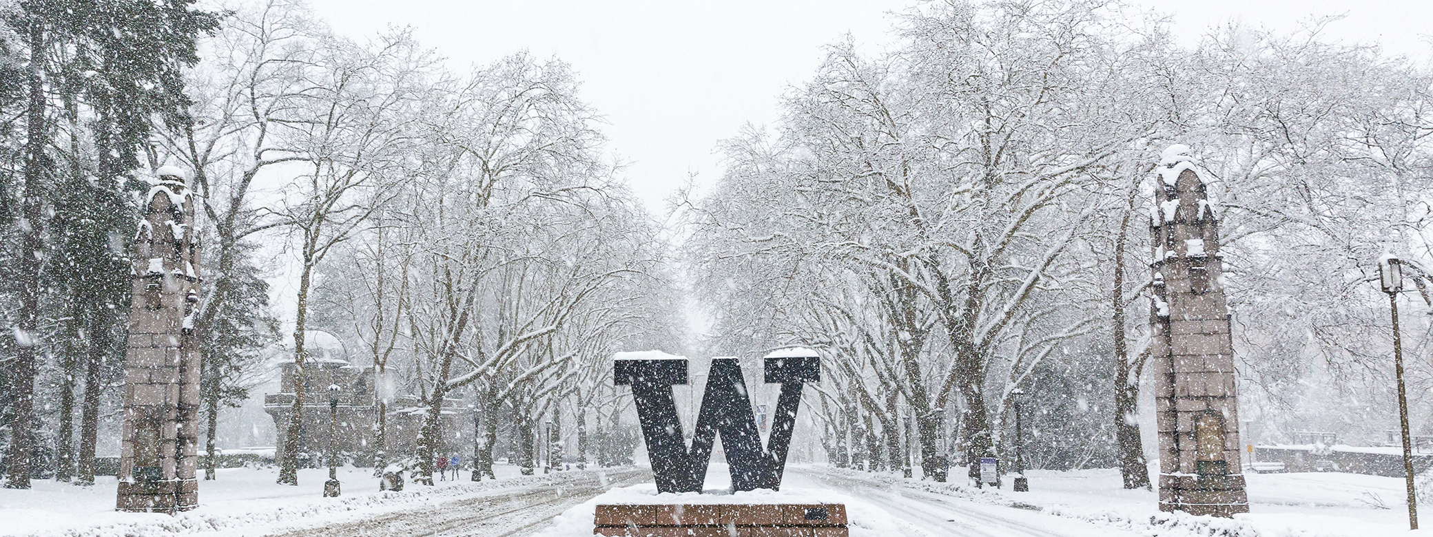 Snowy day with "W" sign at entrance to campus.