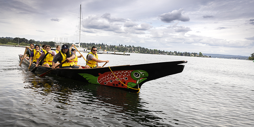 UW Canoe Family paddling in their colorful canoe on a training run on Lake Washington