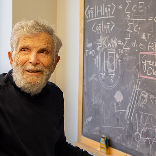Marshall Baker standing next to a chalkboard with physics notations