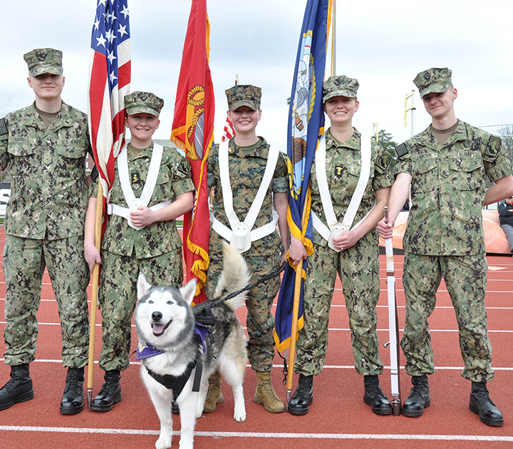 ROTC students holding flags, with Dubs (the UW live mascot) in front. 