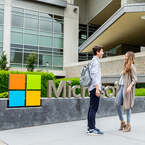 Students standing outside Microsoft offices, with Microsoft logo behind them.