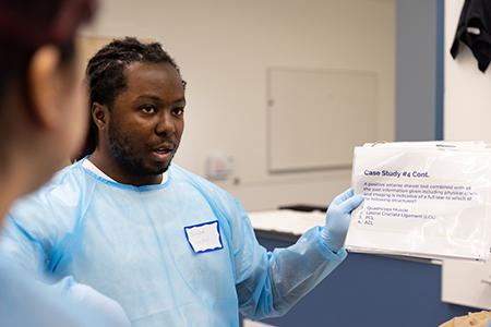 Med student in scrubs holding up an information sheet.