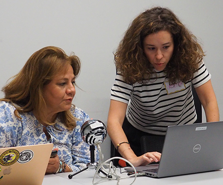 A professor and workshop participant sit facing a microphone and laptop.