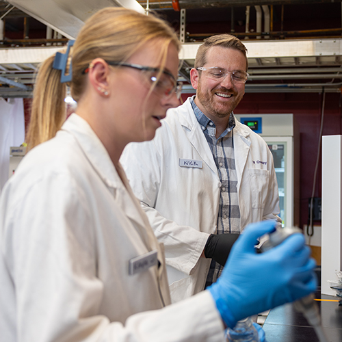 Nick Riley and doctoral student in his lab, in white lab coats.