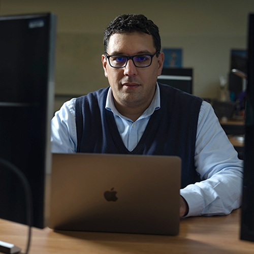 Zaid Harchaoui with open laptop and computers on either side of him.