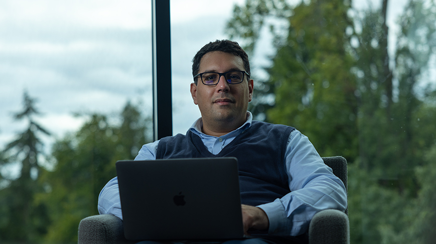 Zaid Harchaoui with open laptop, with window and trees in background.