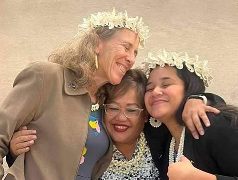 Holly Barker hugging two other women wearing flower garlands in their hair. 