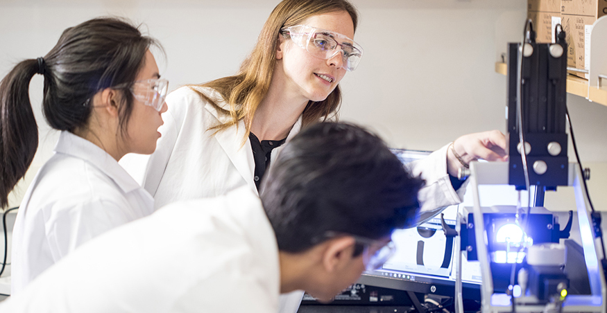 Ashleigh Therberge and research team members looking at equipment in her UW chemistry lab.