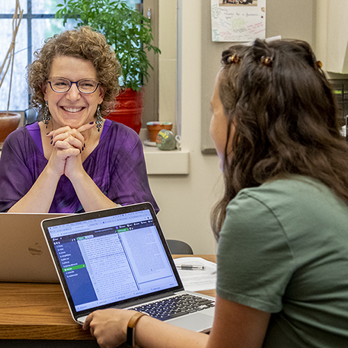 Linguistics professor Emily Bender seated at her desk, across from a student. 