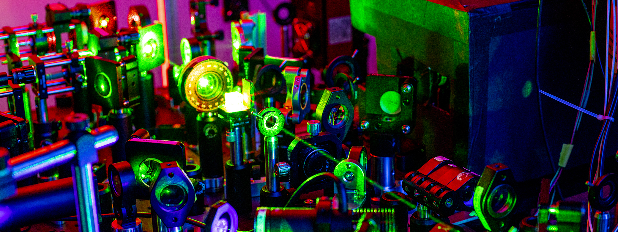 Lens and lasers of a quantum research experiment, altered to appear in bright colors