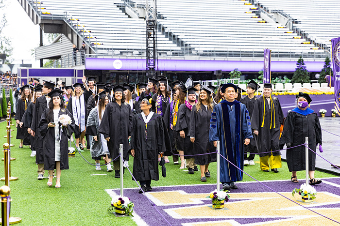 Faculty in cap and gown leading the procession of students into UW Commencement