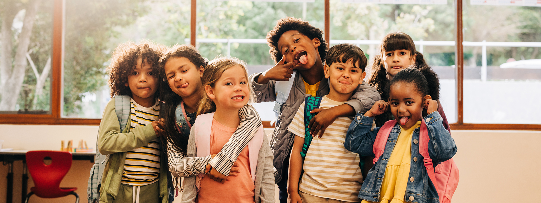 A group of children playfully posing for a photo in a classroom.
