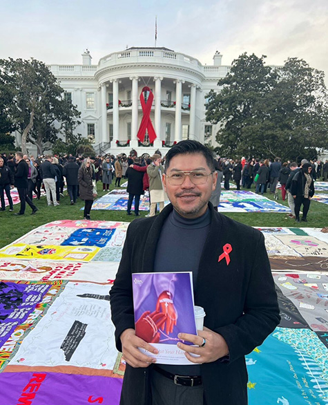 Paulo Pontemayor outside the White House, with the AIDS Memorial Quilt spread out on the lawn behind him. 