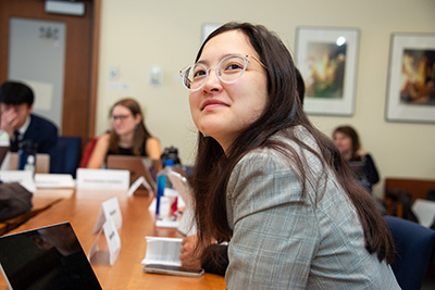 Student at a table looking up at a speaker during Task Force