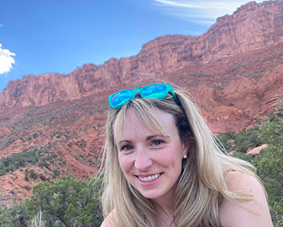 Tessa Olmstead sitting with tall red rock formations behind her.