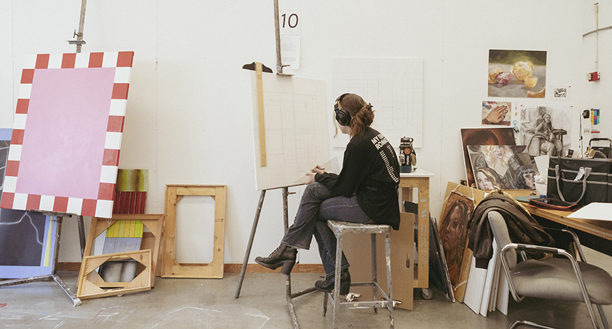 Student seated in front of a canvas in a UW painting studio.