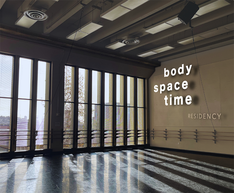 A dance studio with sun shining in and a "body space time" sign on the far wall. dance studio