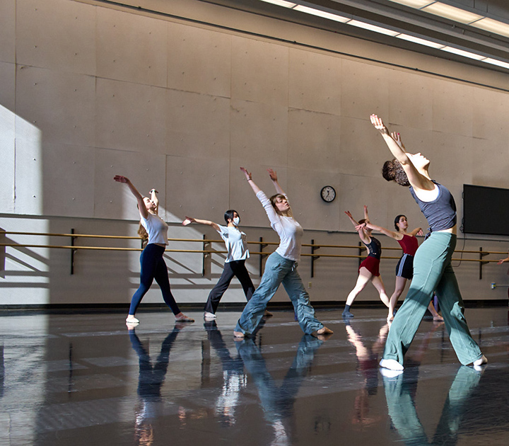 Six students dancing with arms raised in a UW dance studio.